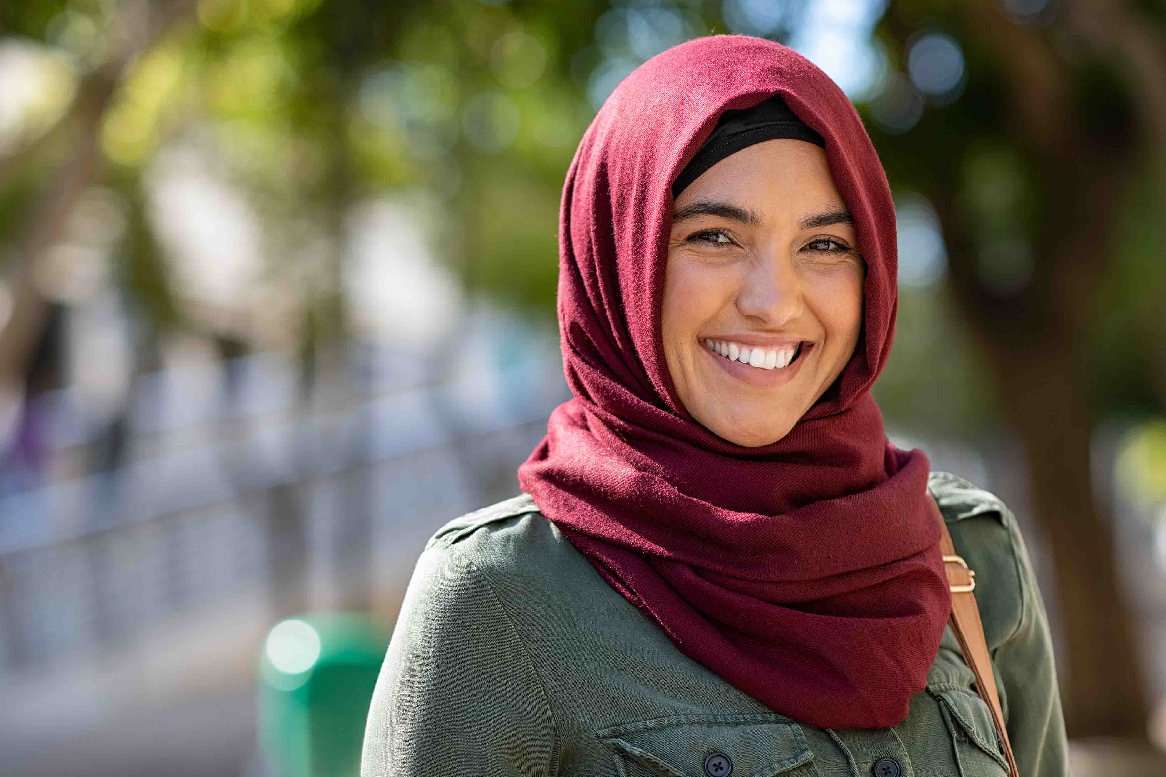 Image shows a young woman wearing a hijab and smiling to the camera.