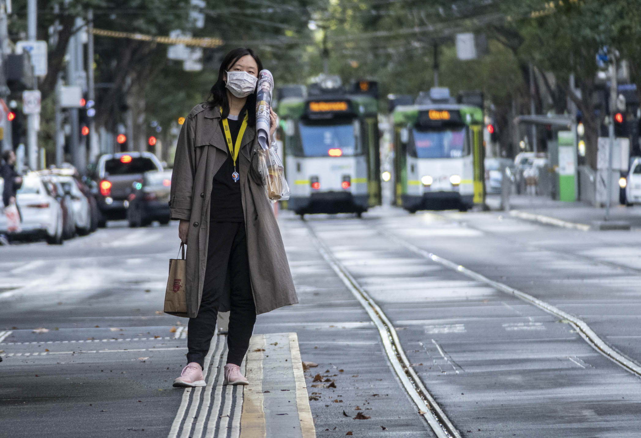 Image shows a person wearing a face mask while waiting at a tram stop during the COVID-19 pandemic.