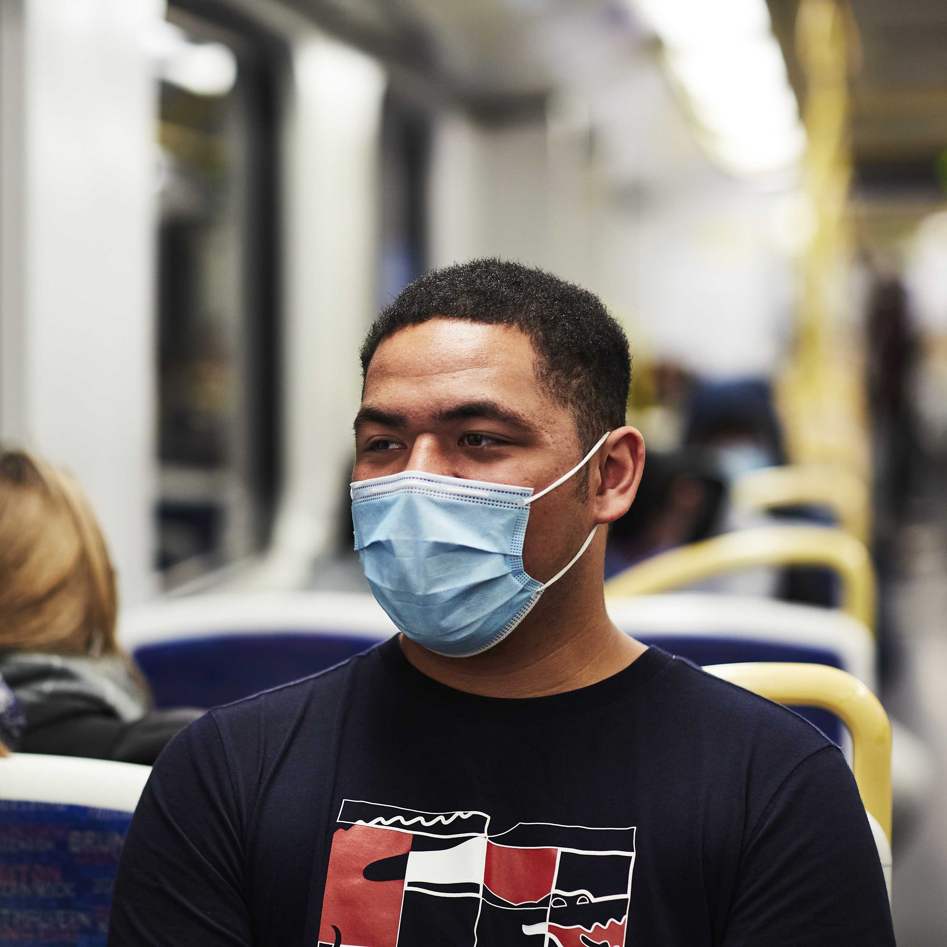 Image shows a person wearing a facemask while travelling on a train during the COVID-19 pandemic.